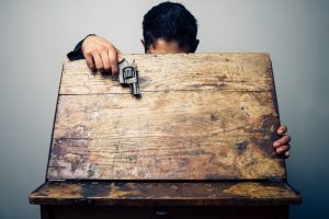 A young boy pulls a hidden gun out of his school desk