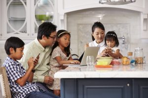 Family uses laptop and other devices over breakfast