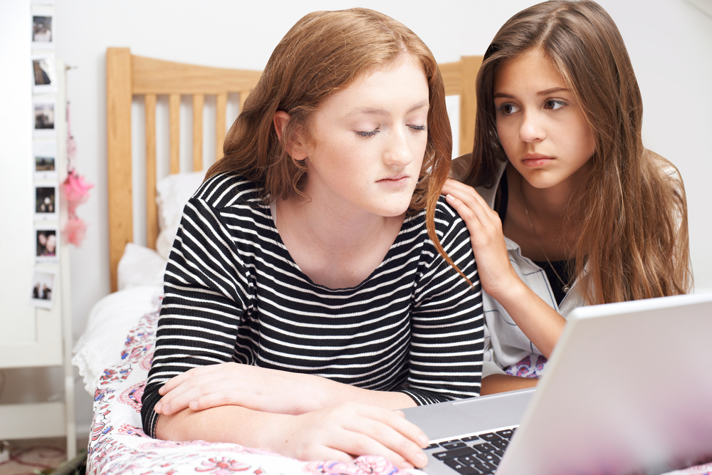 A teen girl comforts a friend who is being bullied online