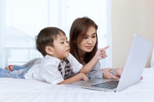 Mother and son look at laptop together.