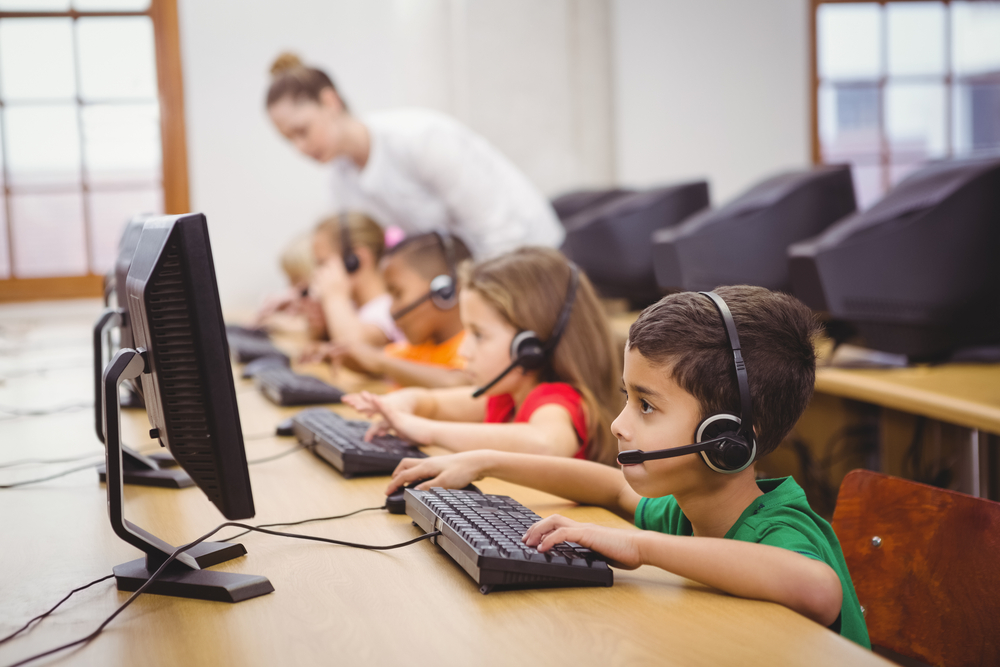 Elementary school students use headsets in computer class.