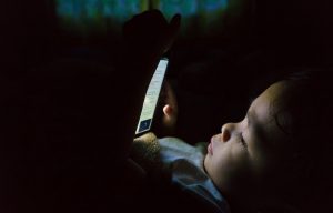 Young boy with tablet in bed