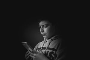 Crying boy holding smartphone.