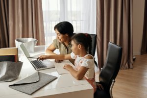 Mother helps her young daughter with online homework.