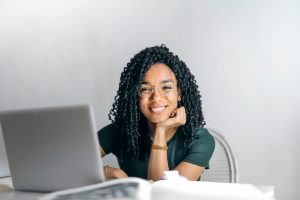 Teenage girl working at computer looks at camera and smiles.