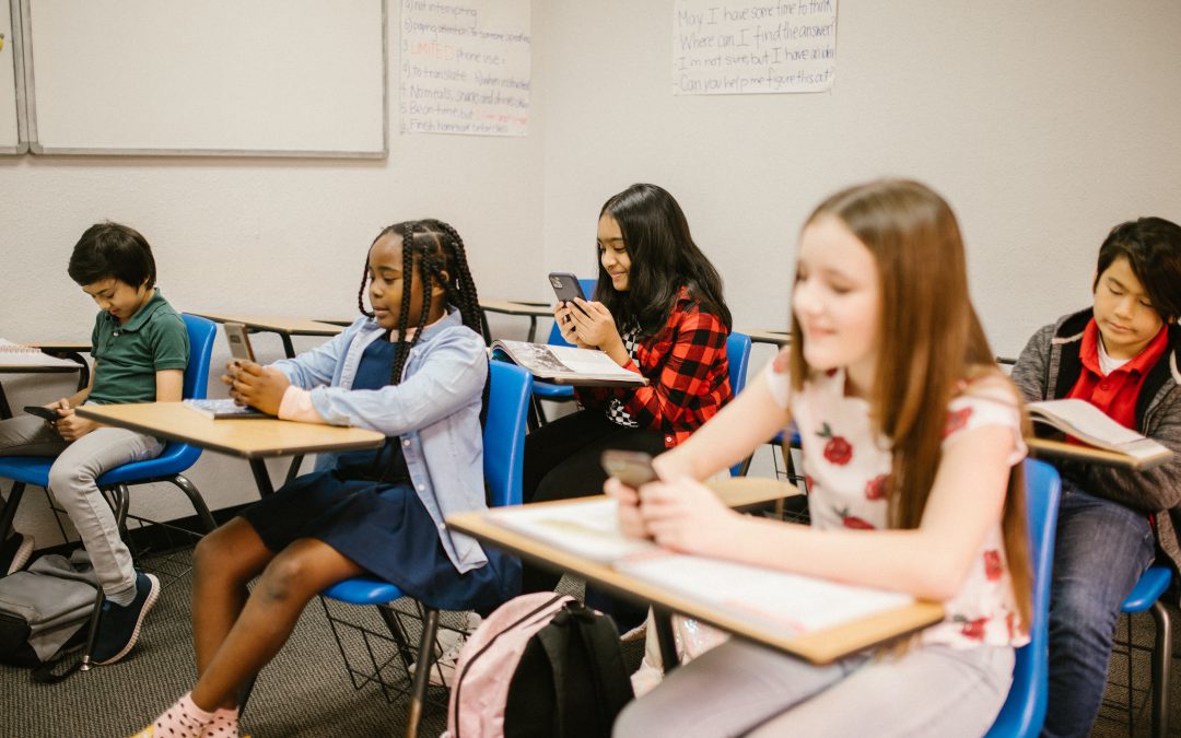 A group of middle schoolers use cell phones in a classroom