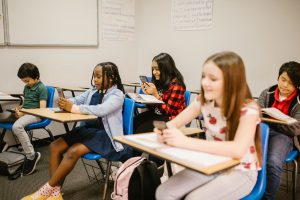 A group of middle schoolers use cell phones in a classroom