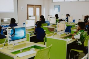 A computer classroom with bright lime green desks. Students work independently at their desktop computers.