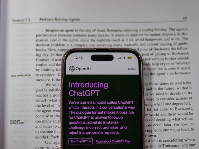 iPhone with ChatGPT webpage open sitting on top of a page in a textbook.